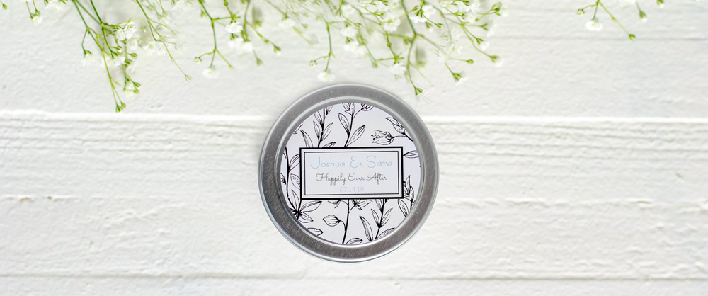 Candle tin wedding favor with white floral label on the lid. 