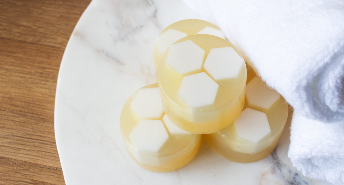 Honeycomb melt and pour soap bars on marble plate sitting next to white towels. 