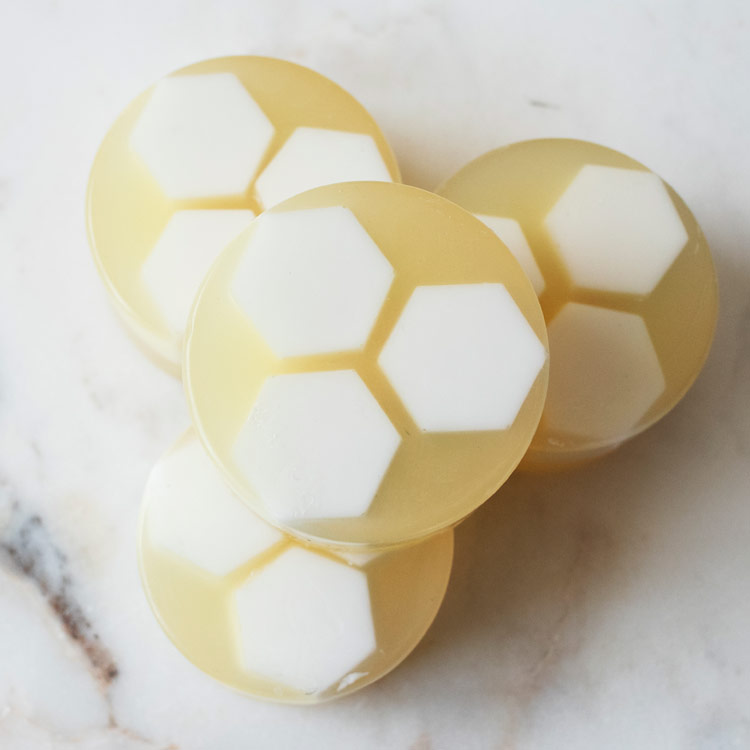 Honeycomb facial soaps stacked on a marble countertop.