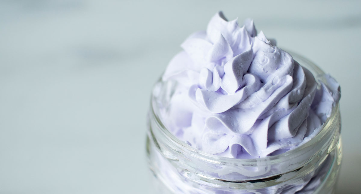 Purple whipped bath soap in jar on table. 