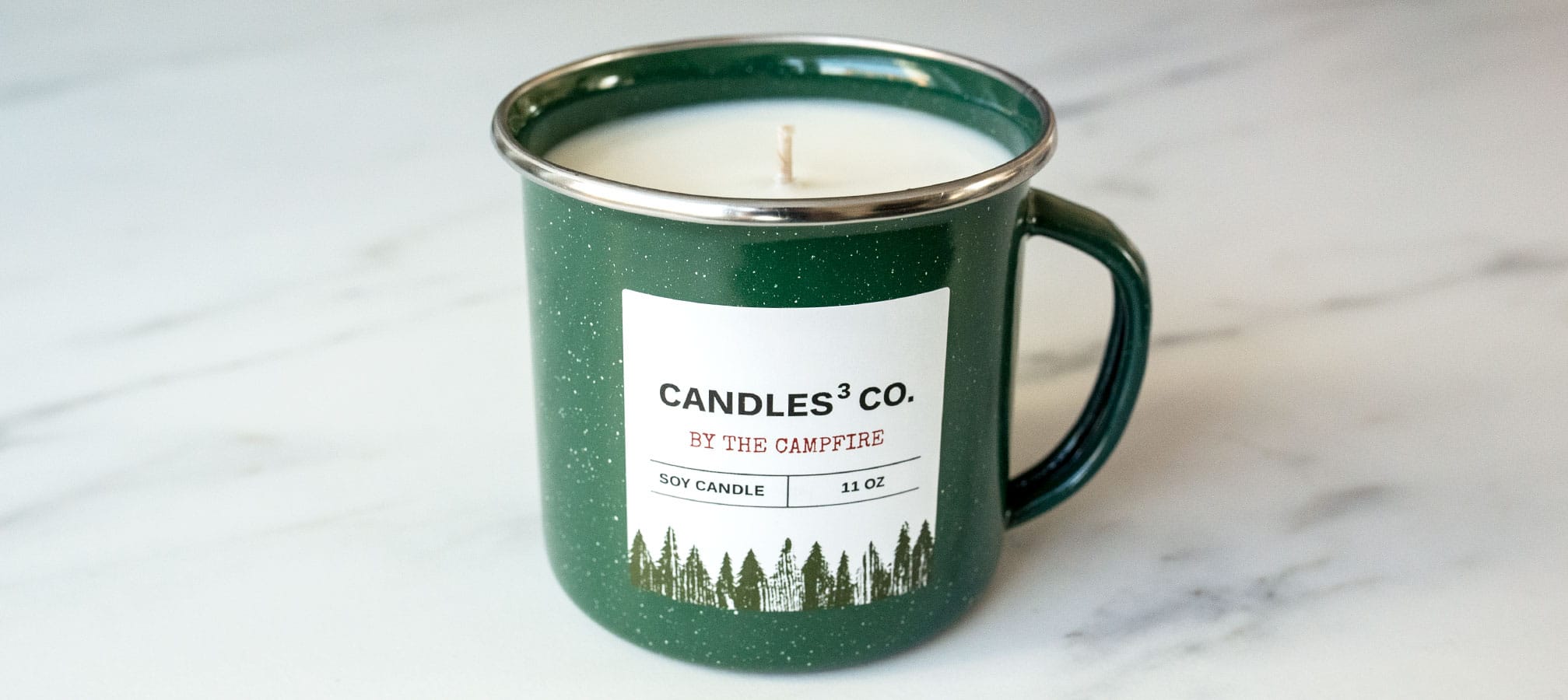Close up of a green enamel mug candle with a label.