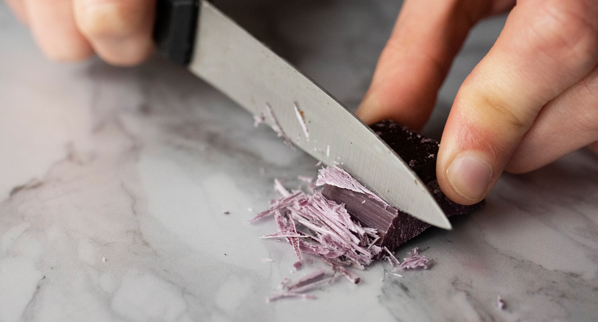 Cutting pale pink candle dye block with a knife