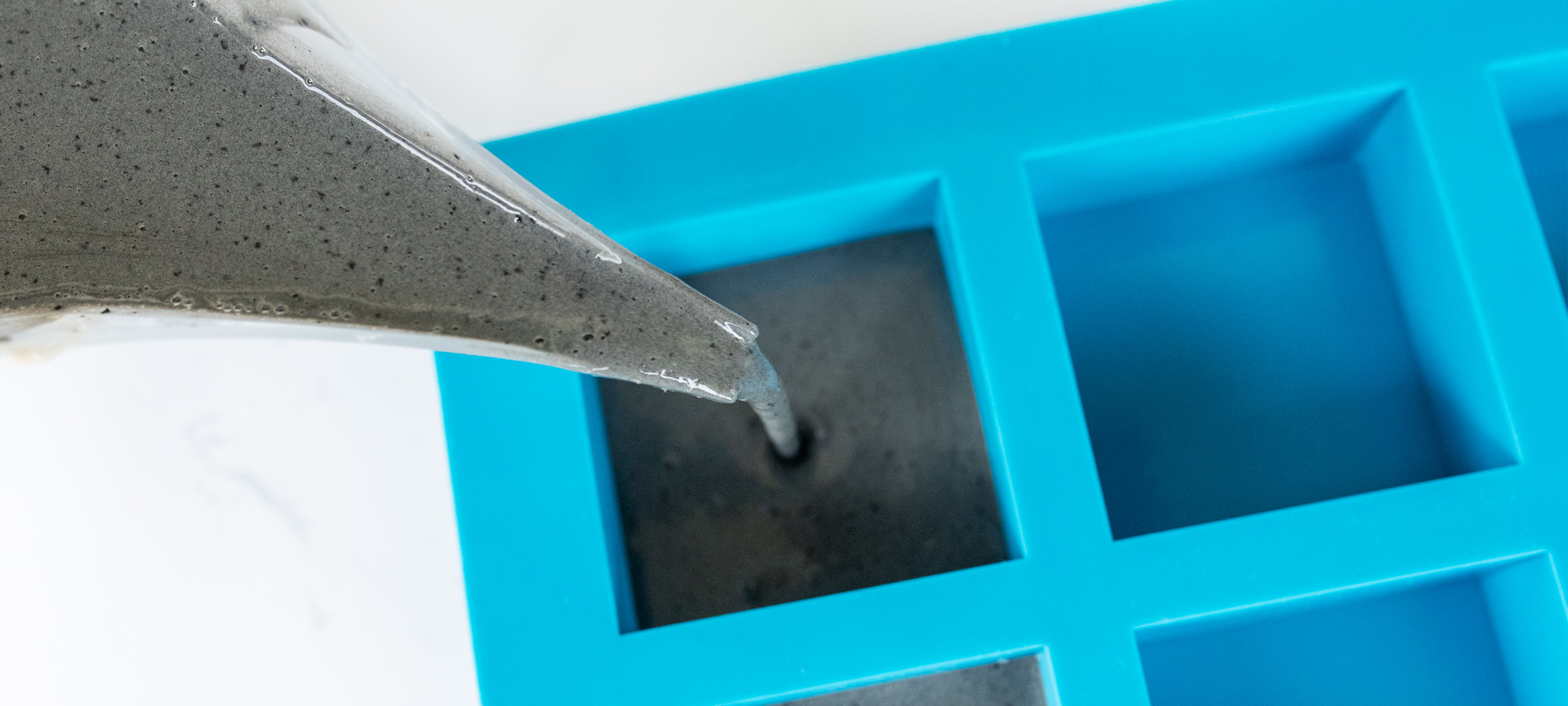 Pouring exfoliating soap into square silicone soap mold.