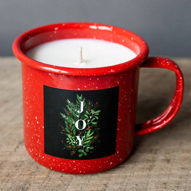 Red holiday mug candle on wood table top. 