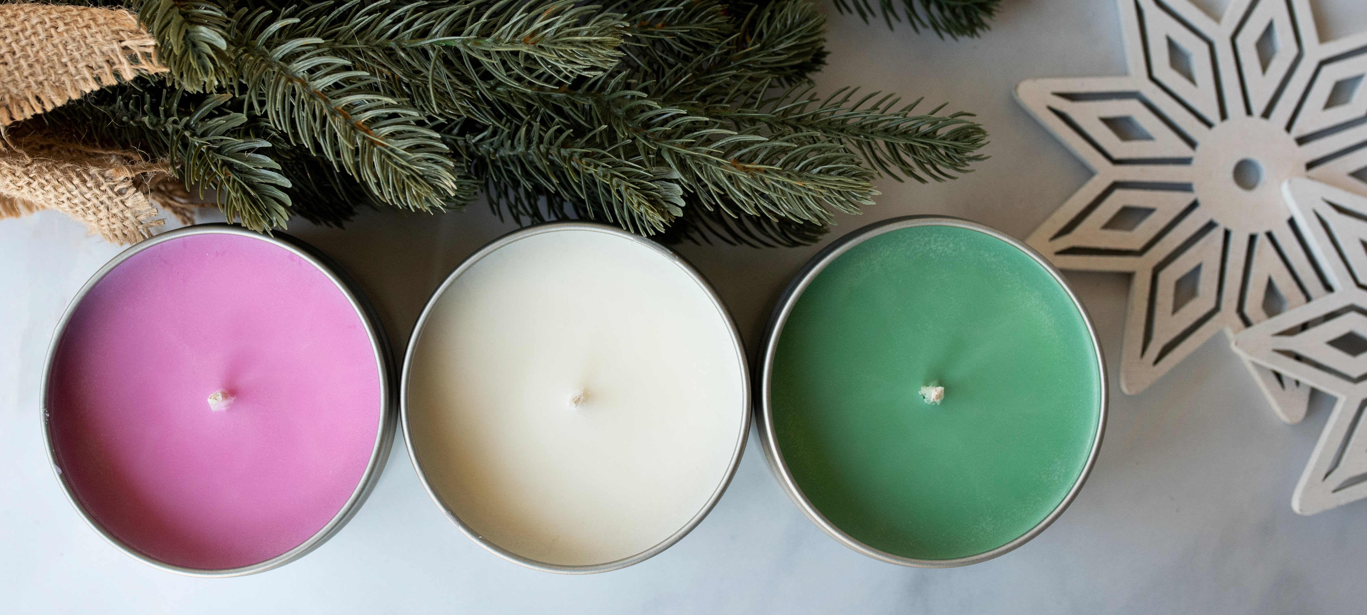 Soy candle tins lined up in holiday colors.