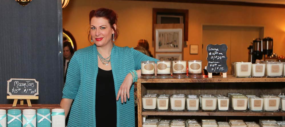 Witty Wicks founder standing next to  her candles and booth. 