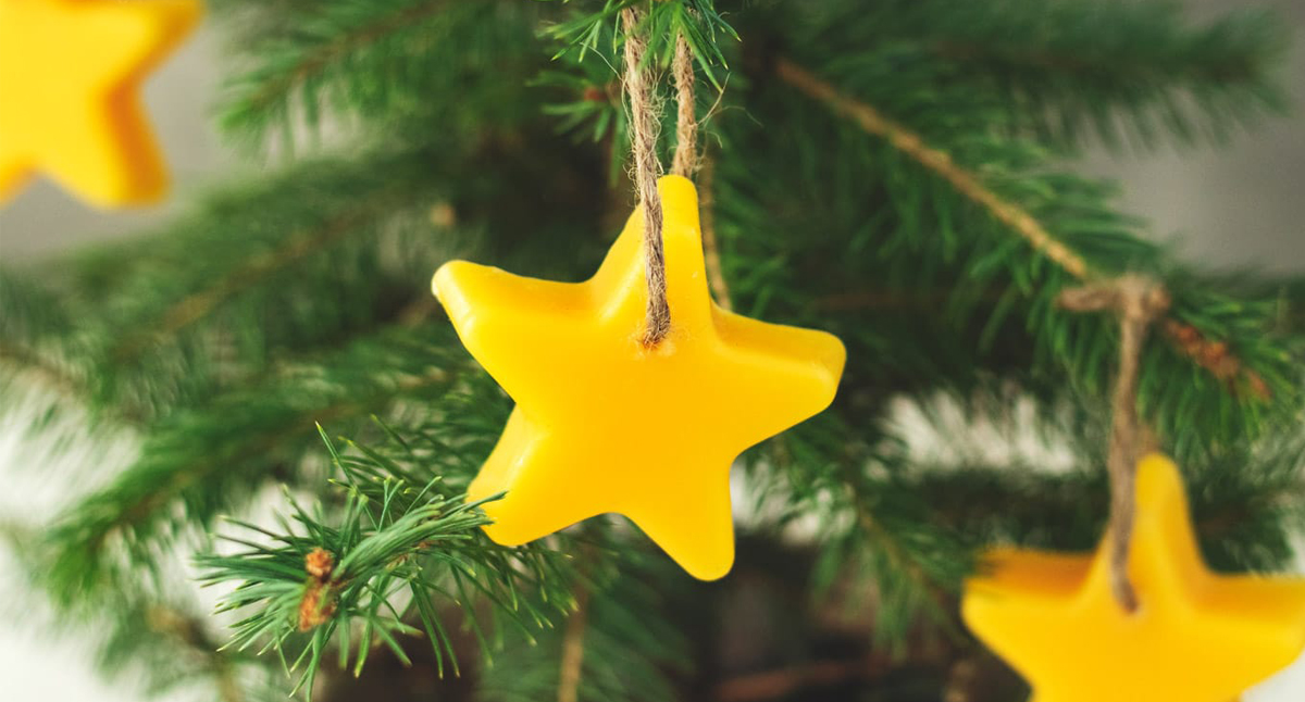 Yellow beeswax, five point star Christmas ornament on Christmas tree. 