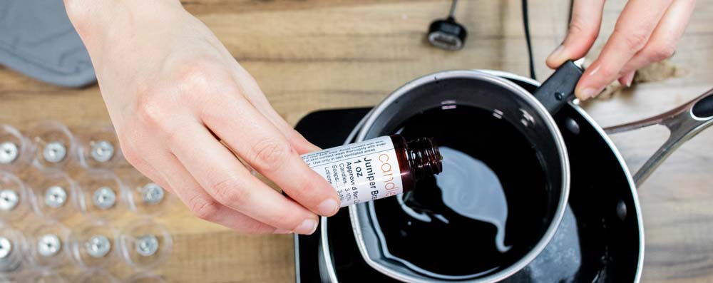 Pouring fragrance oil into melted soy wax.