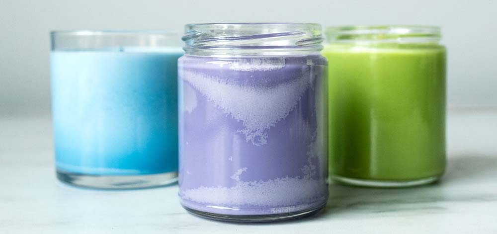 C-3 cargill soy wax lab notes color Three colorful candles on a white table, next to a white background.