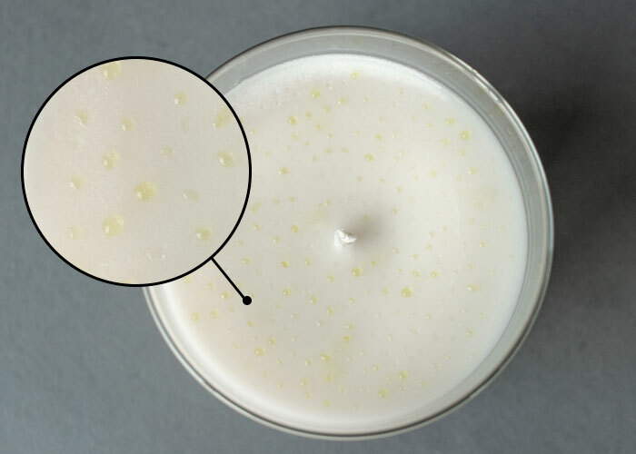 Top of a white soy wax candle with fragrance leaching out of the wax. 