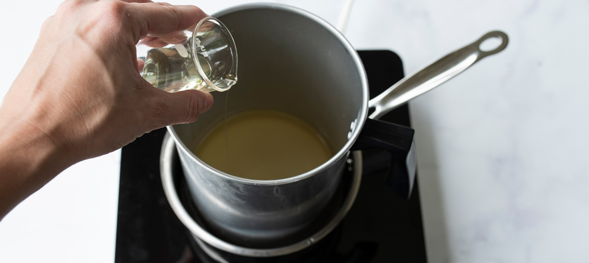 Pouring fragrance oil into melted wax.