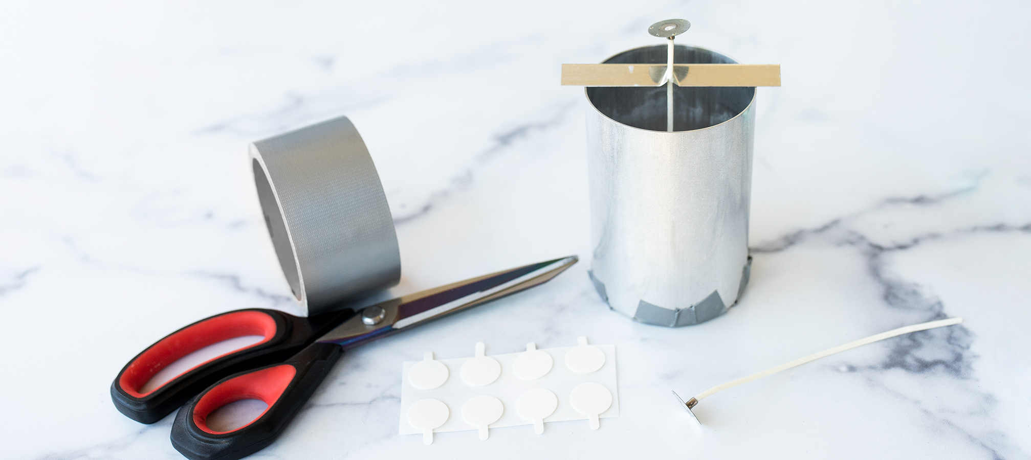 How to wick a pillar mold Scissors, molds, tape, wick, and other assorted materials.