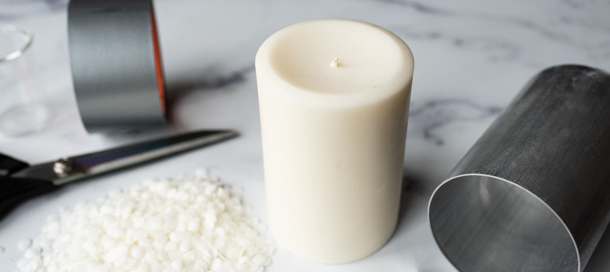 A pillar candle with a mold and other supplies.