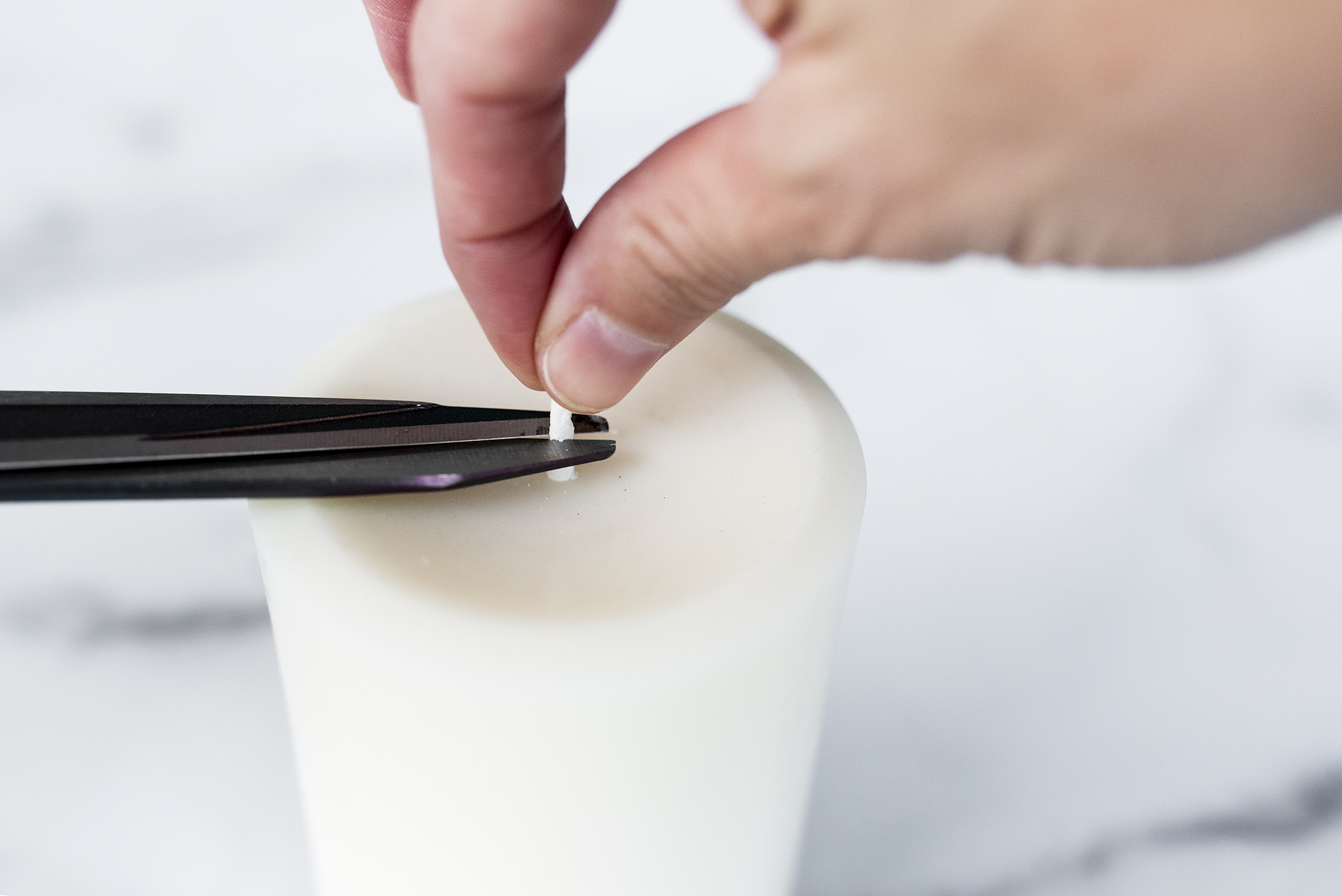 Trimming candle wick on a pillar candle.