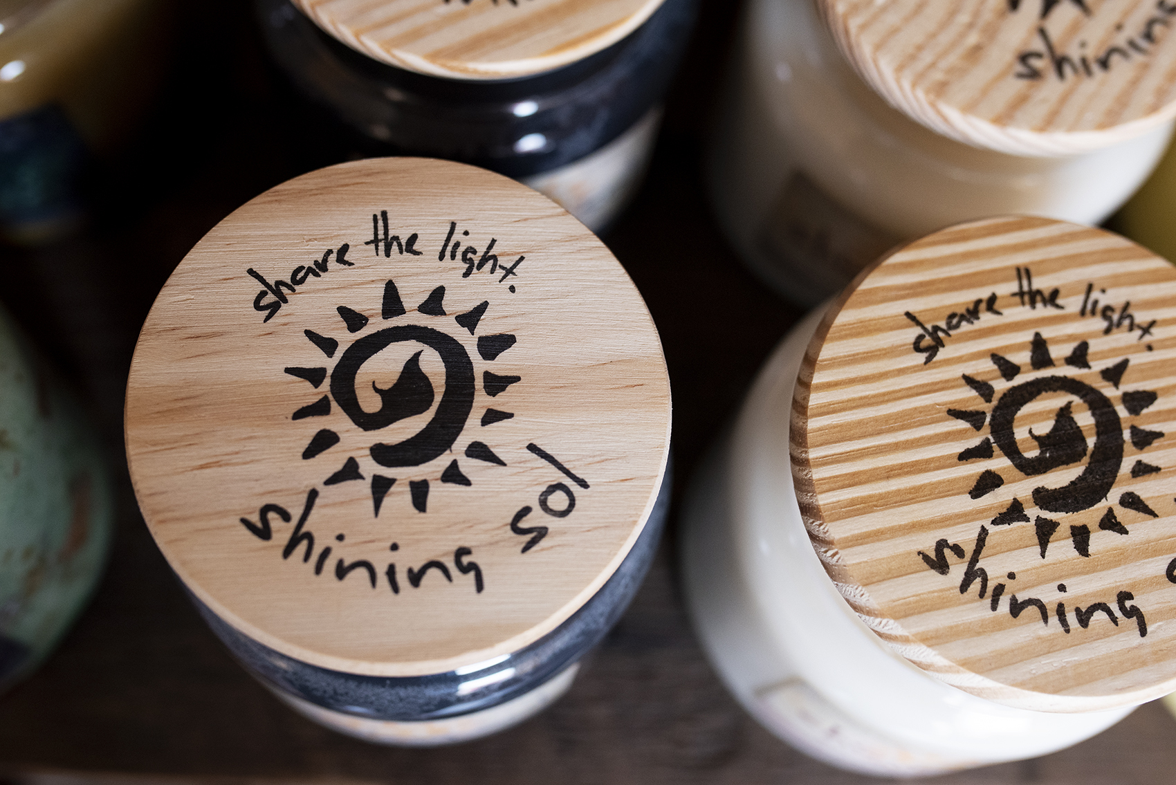 Candle lids with Shining Sol logo on top.