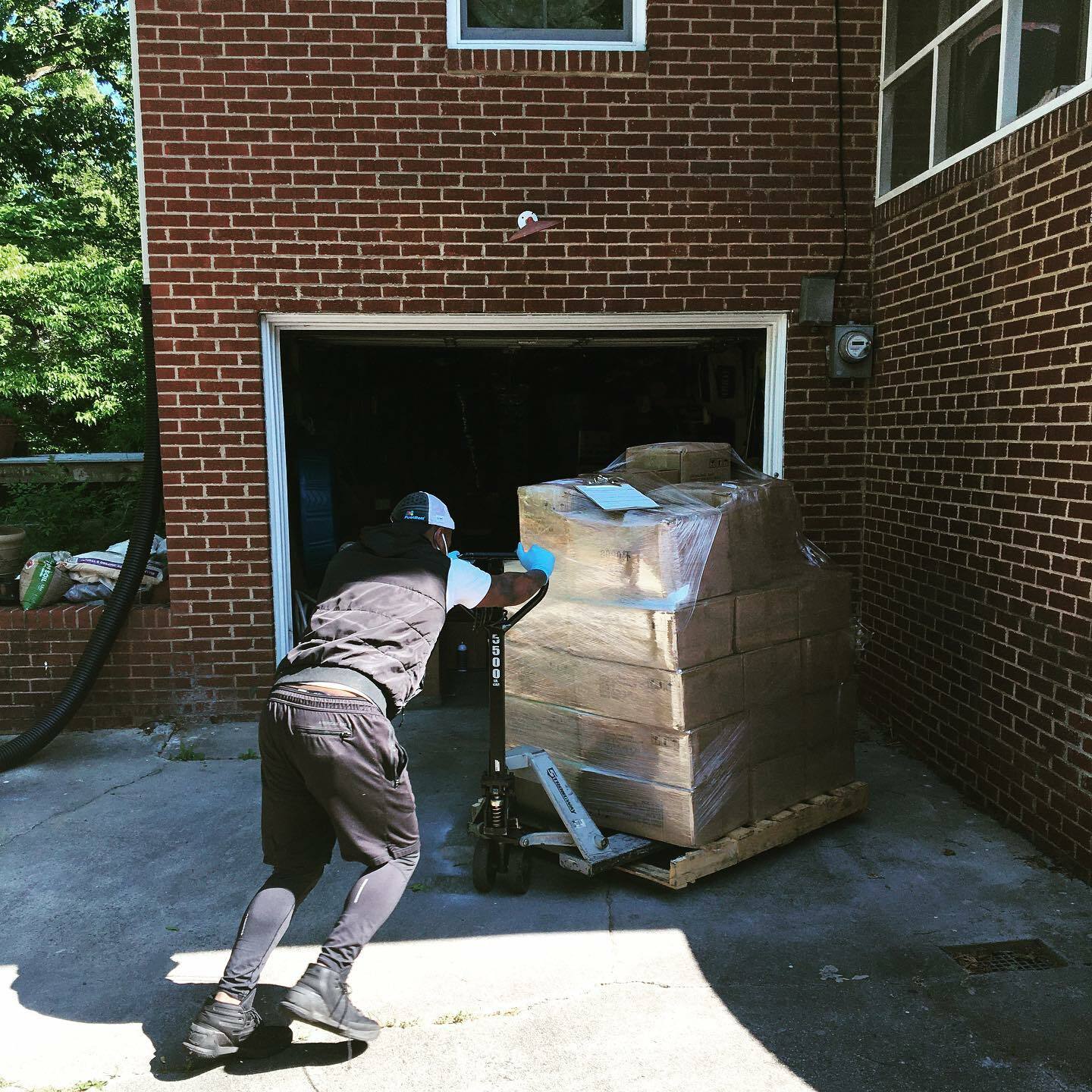 A person pushing a large pallet of candle making supplies on a dolly.