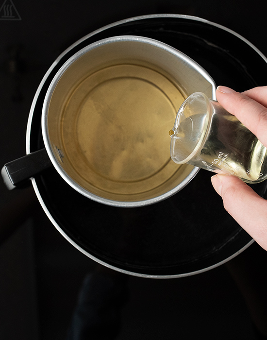 Pouring fragrance oil into melted wax.