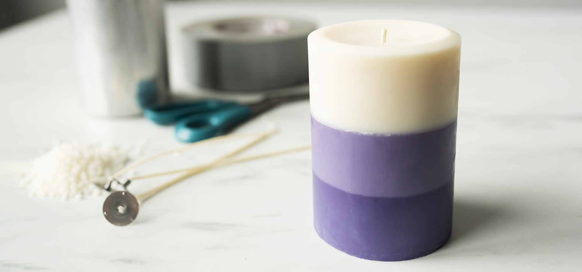 A layered pillar candle with candle making supplies.
