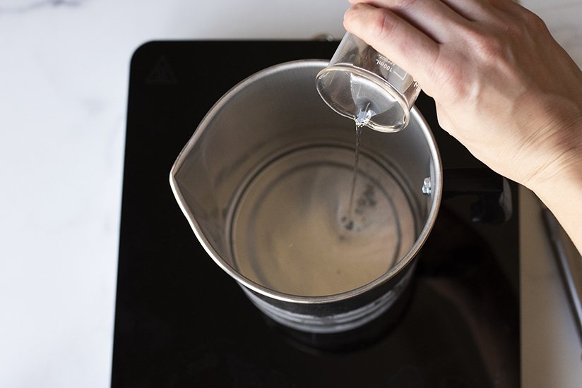 Pouring fragrance oil into melted wax.