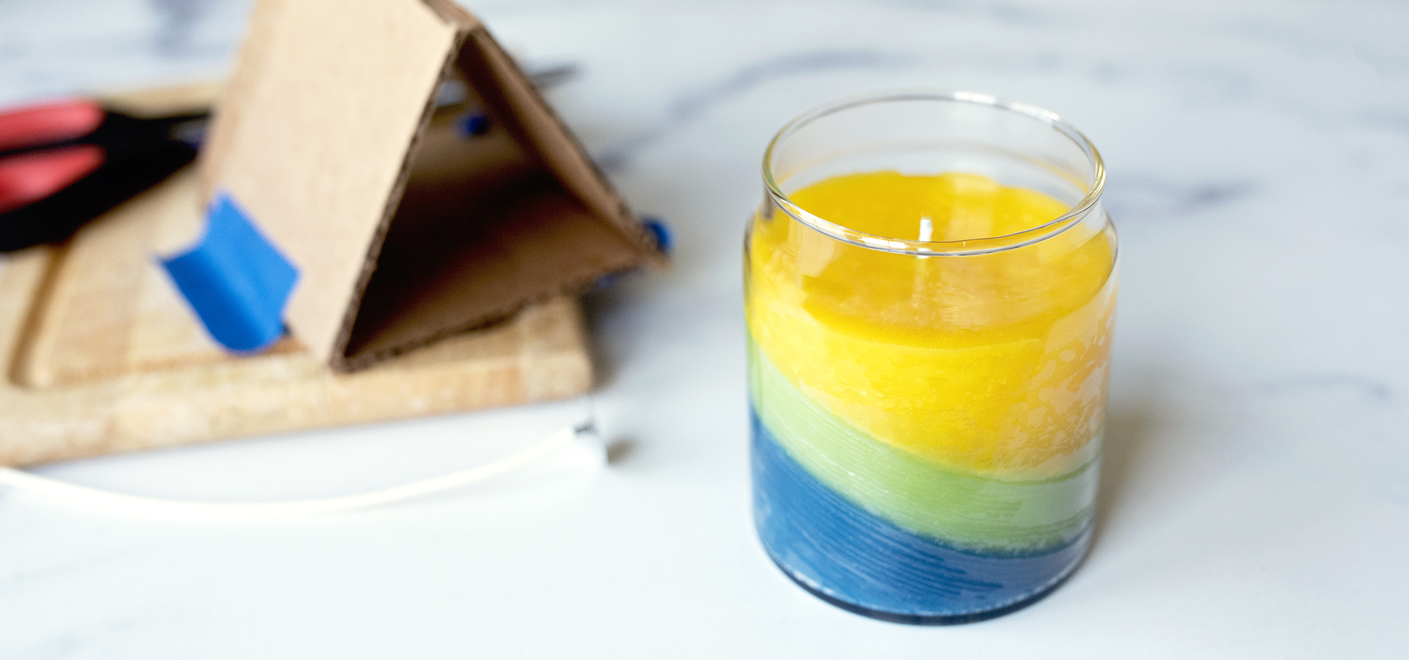 Tilted colored layer container candle.