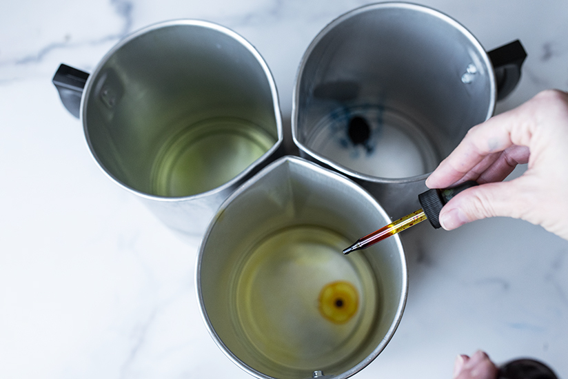 Adding liquid candle dye to pouring pitchers.