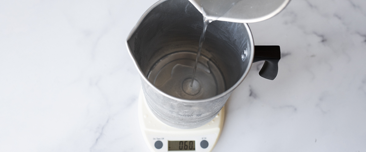 Pouring wax into a pouring pitcher on a digital scale.