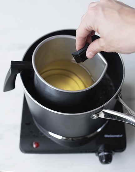 Adding half of a dye block to melted wax.