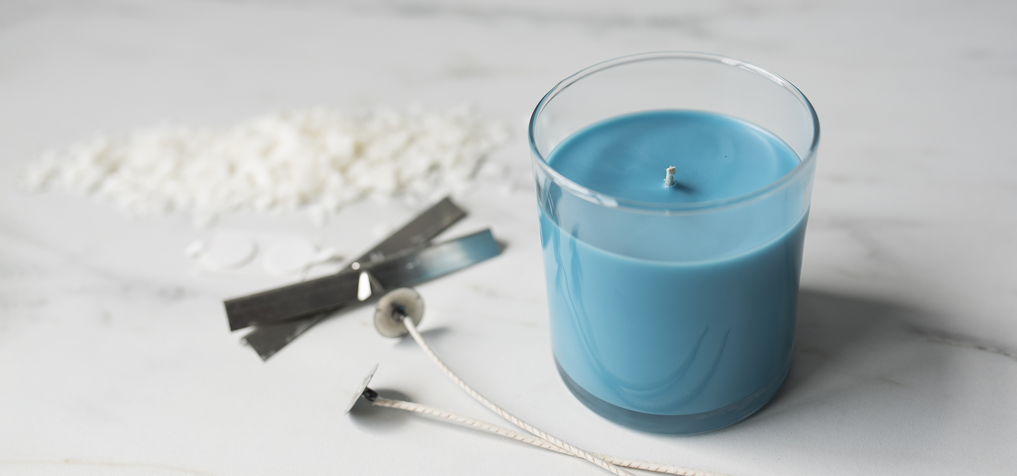 A soy candle with candle making supplies.