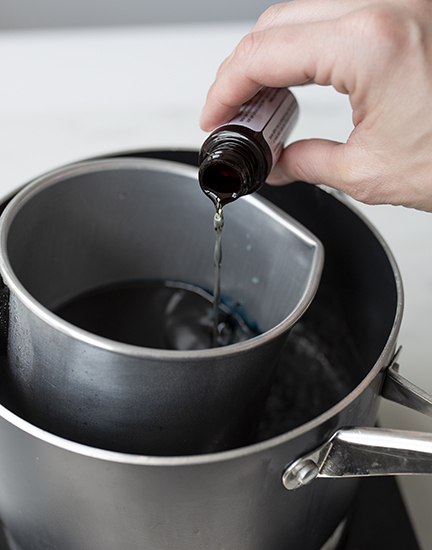 Pouring fragrance oil into melted wax.