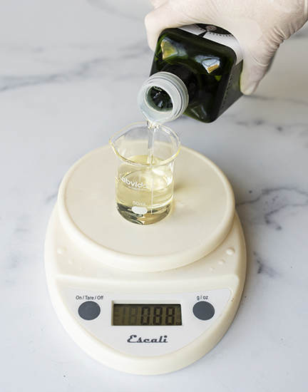 Pouring sunflower oil into a beaker on a scale.