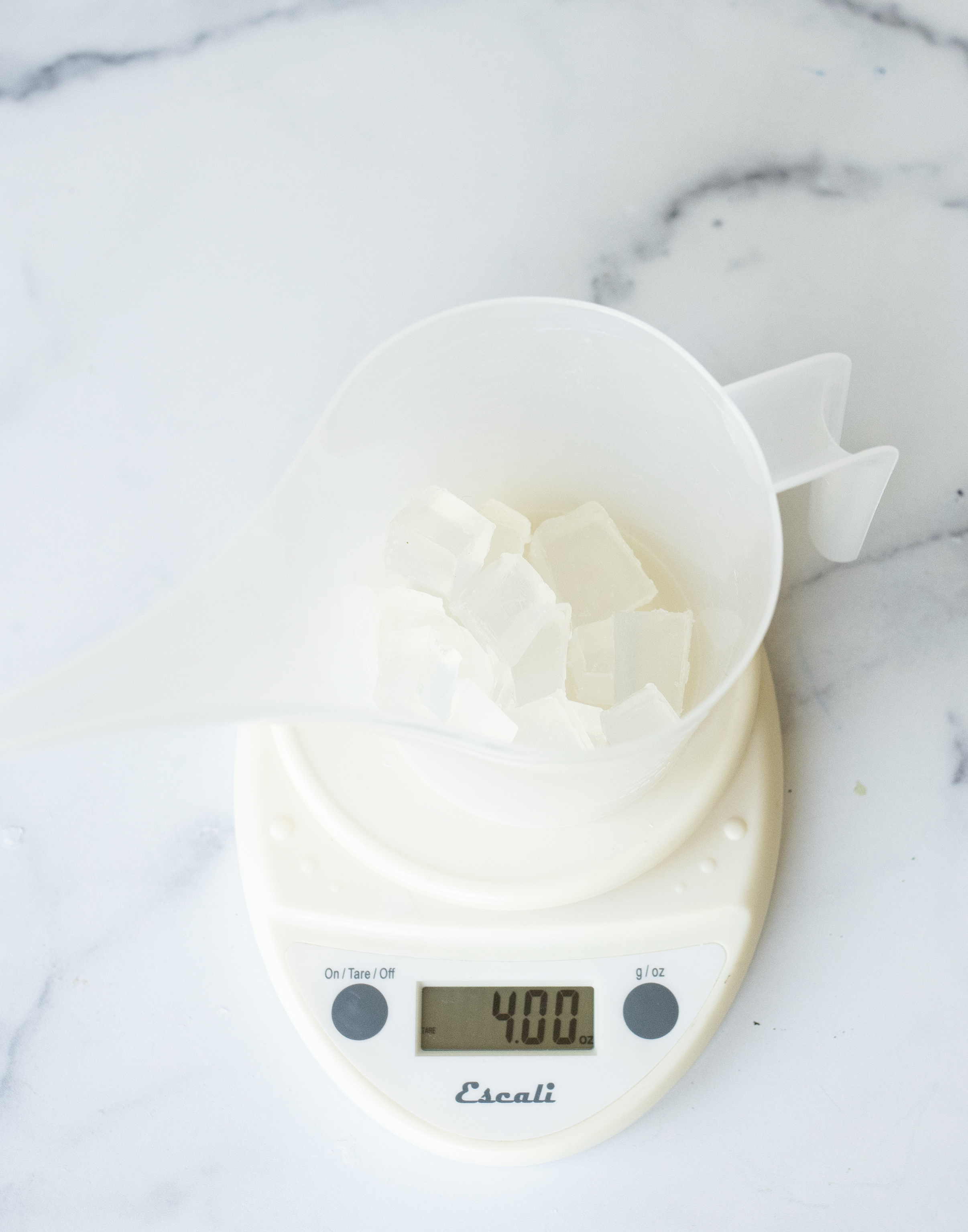 Adding soap base to a funnel pouring pitcher on a scale.