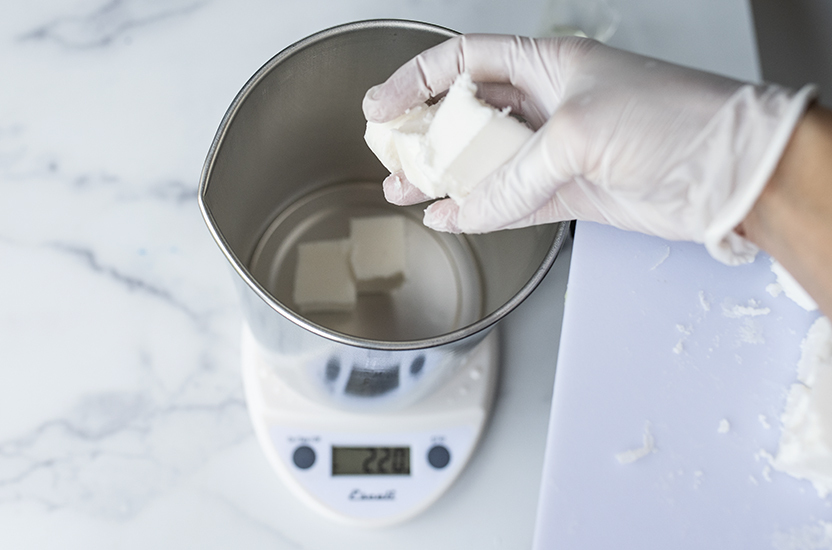 Adding cubed cosmetic base into a pouring pitcher.