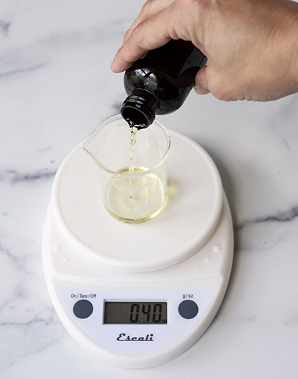 Pouring fragrance oil into a beaker.