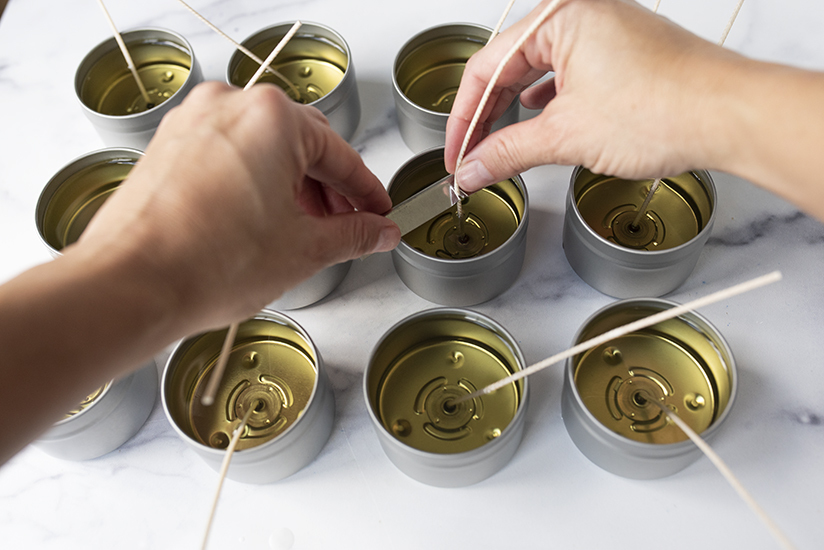 Adding wick bars to candle tins.