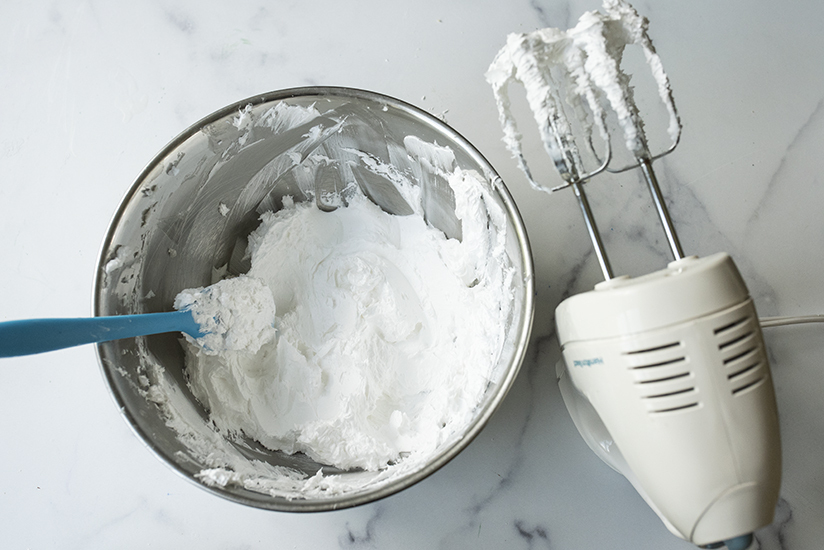 Whipped foaming bath butter base in a bowl with a silicone spatula.