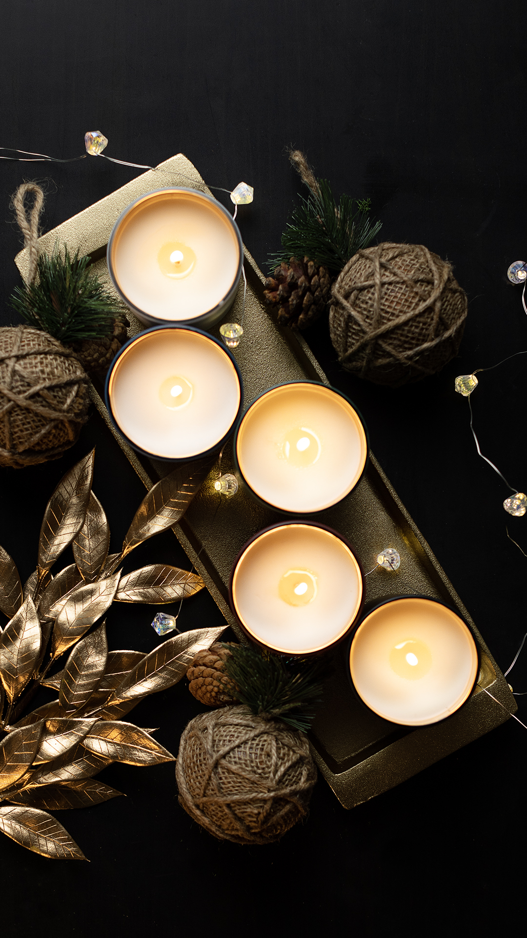 Matte tumbler candles lit with string lights and golden props.
