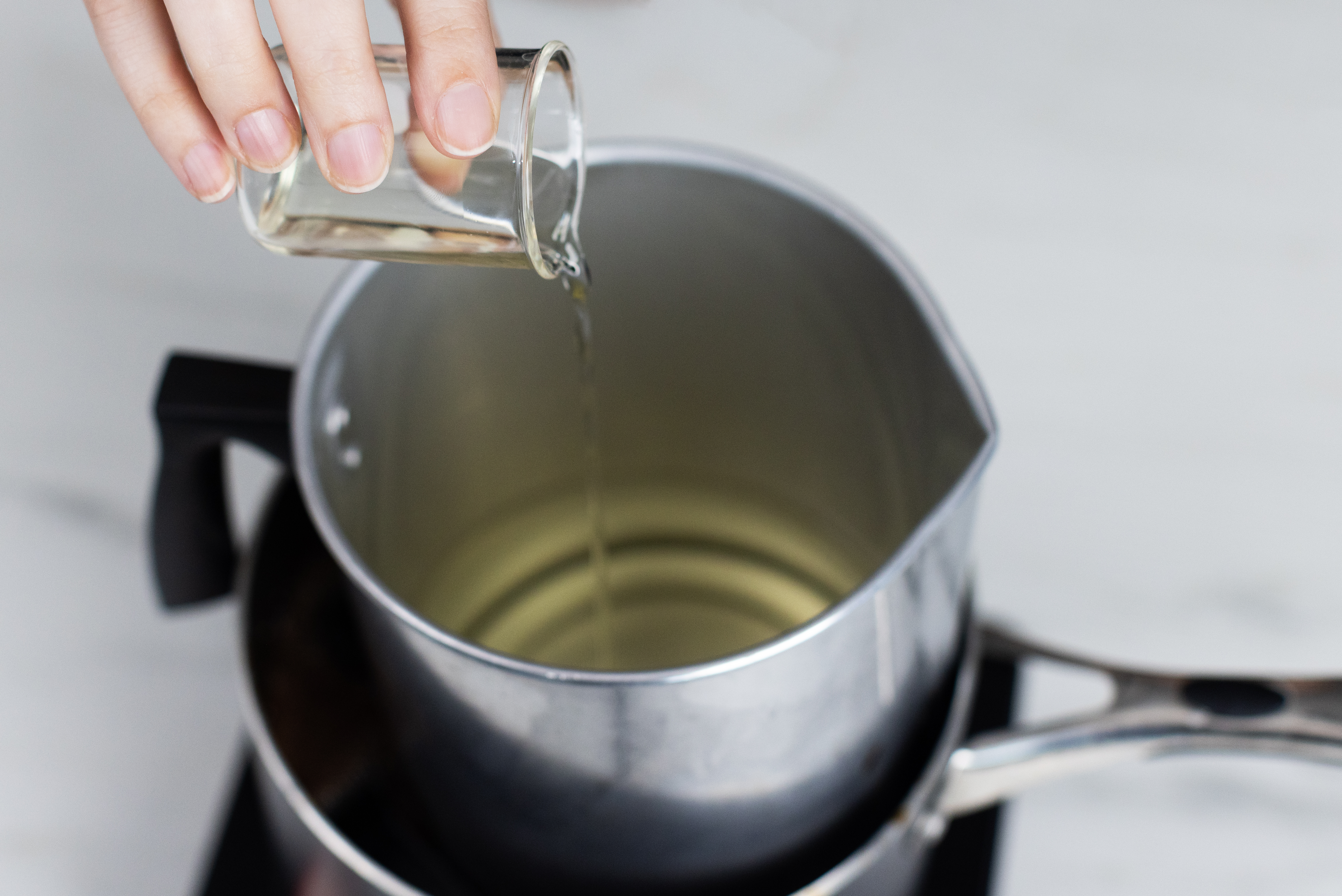 Pouring fragrance oil into melted wax.