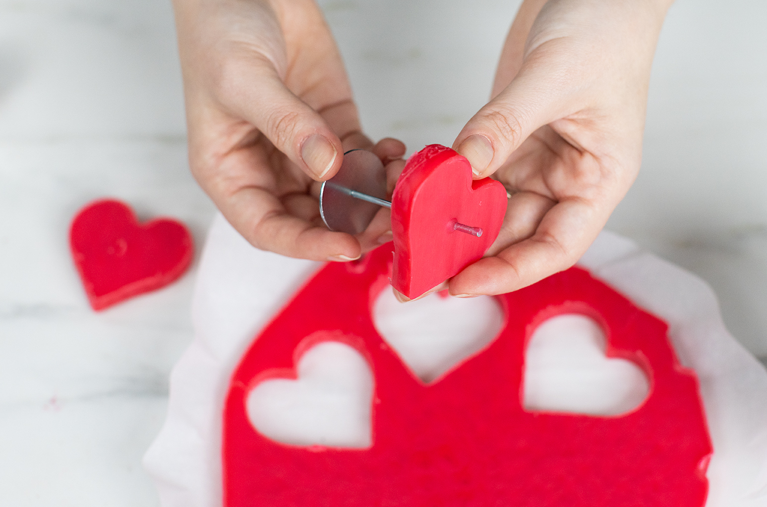 Poking a wick pin through wax heart embed.