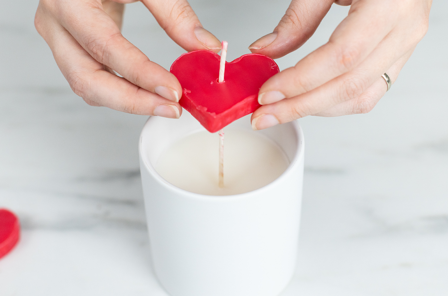 Placing heart embed on candle wick.