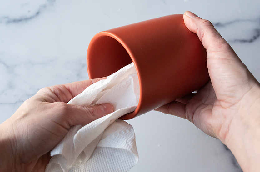 Cleaning out modern ceramic jar with paper towel.