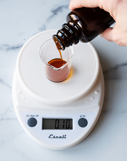 Pouring essential oil into beaker.