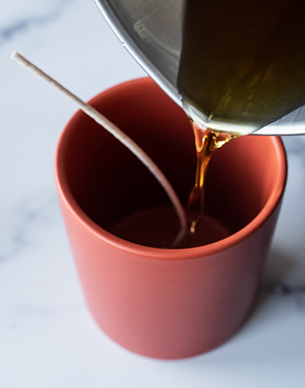 Pouring wax into candle jar.