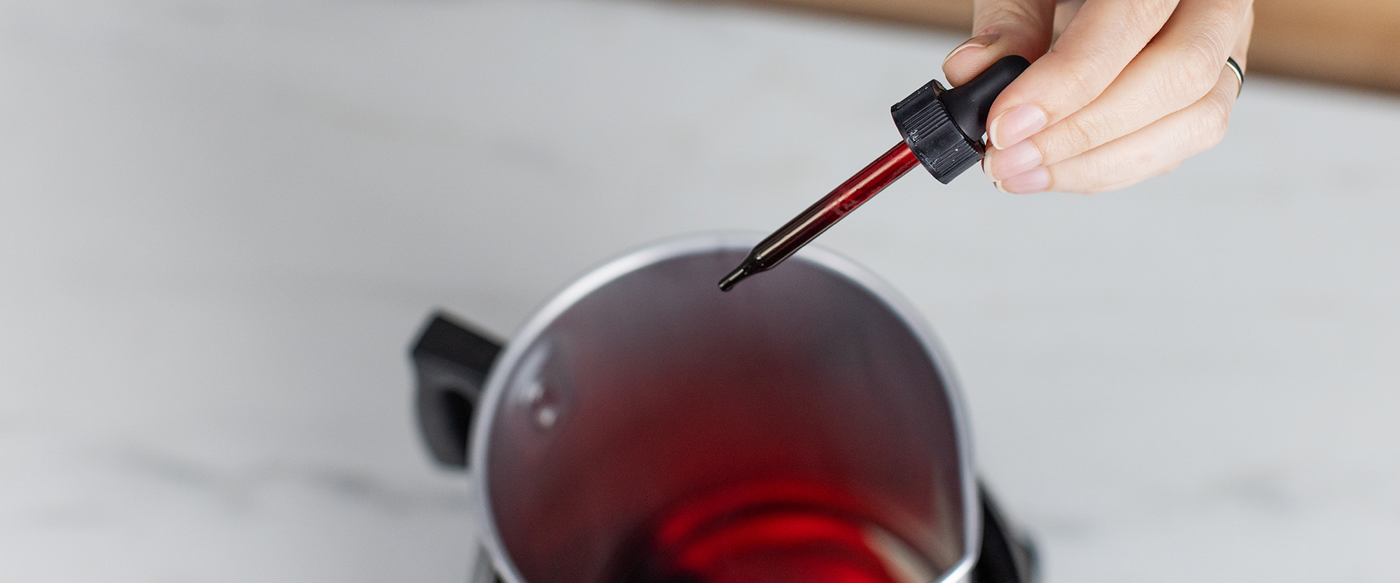 Adding red candle dye to melted wax.