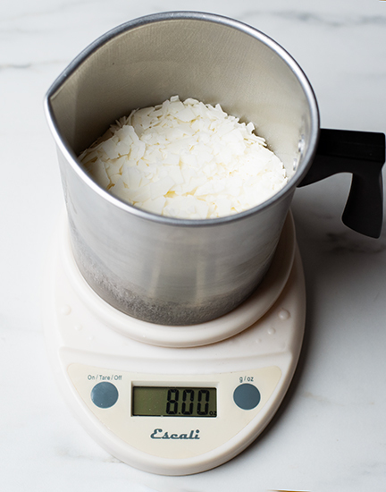 Weighing soy wax flakes on a digital scale.