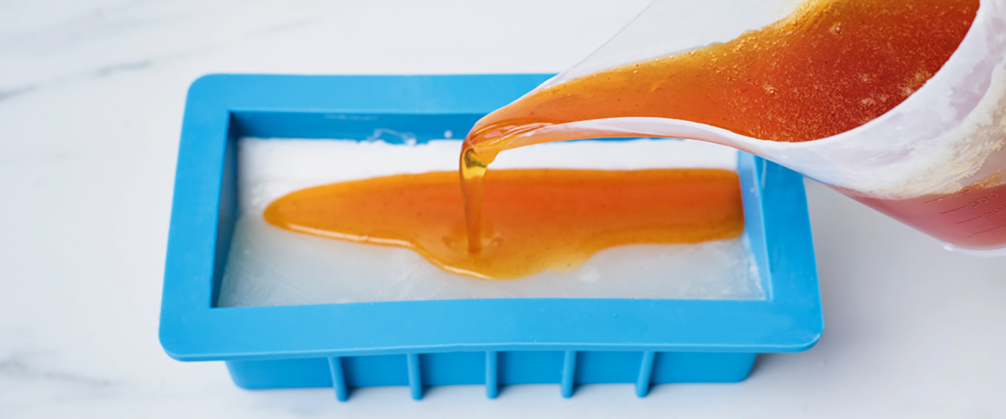 Pouring soap into a soap mold.