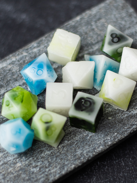 Blue, green, white, and black wax melt square on a black surface.