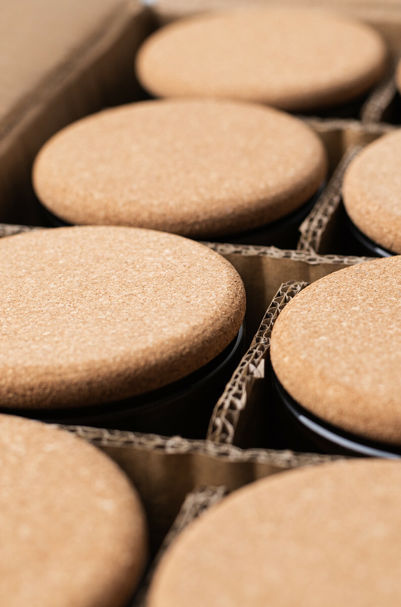 Overhead, angled view of candles in a divided cardboard box with cork lids