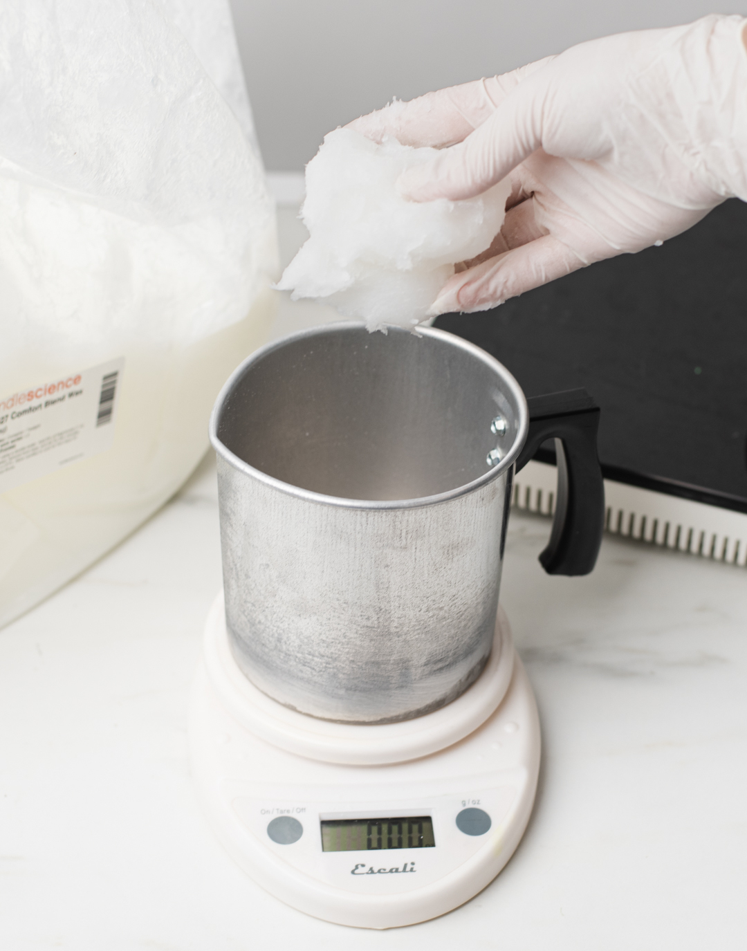 Adding wax to a pouring pitcher.