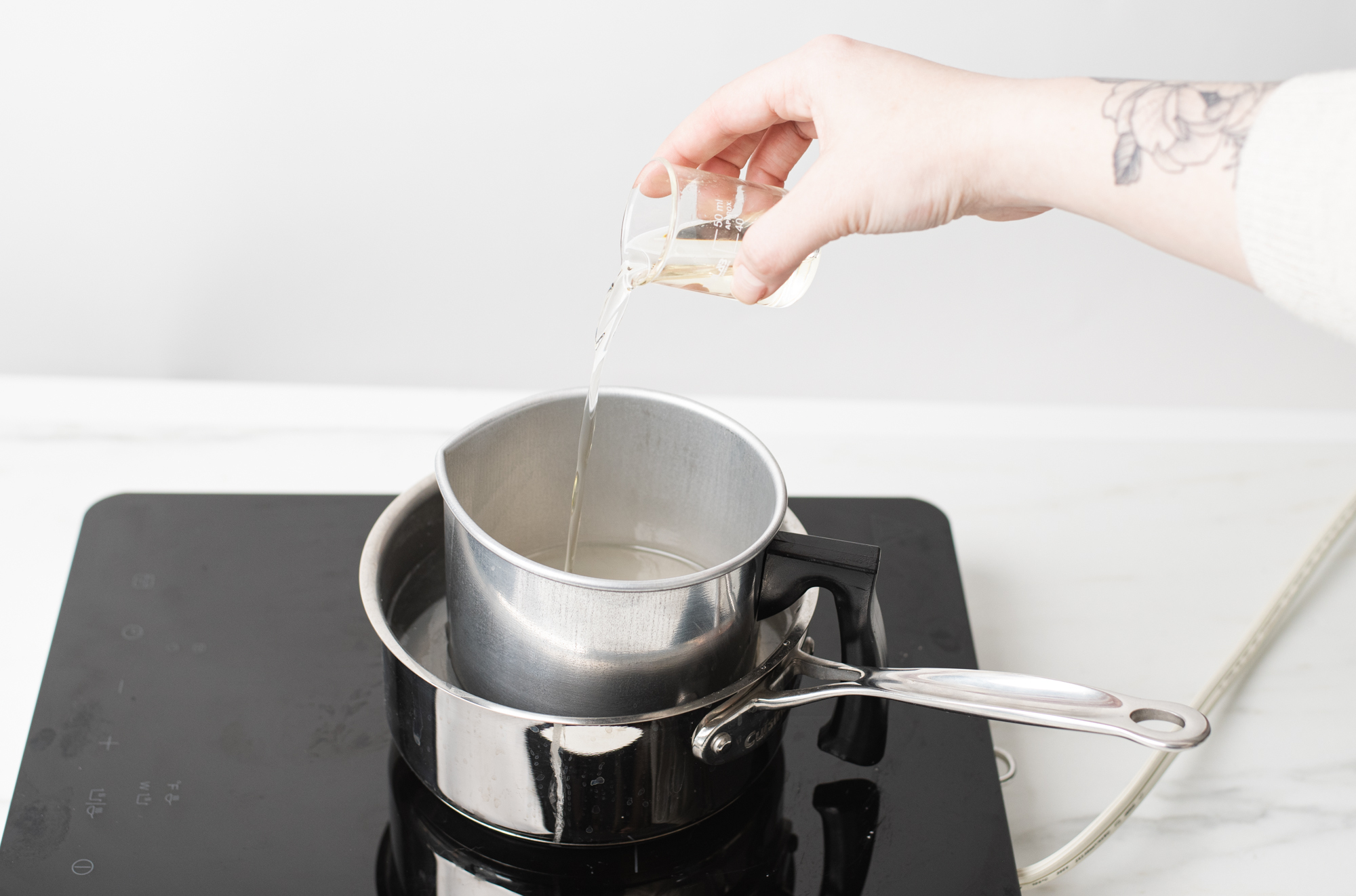 Pouring fragrance oil into melted wax.