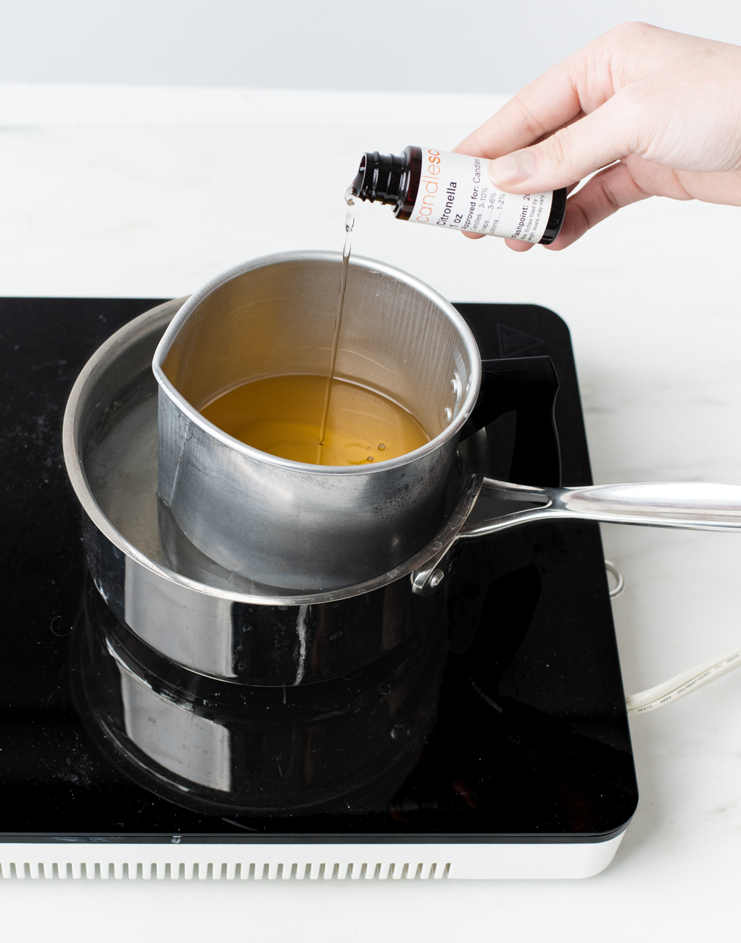 Pouring fragrance oil into melted wax.